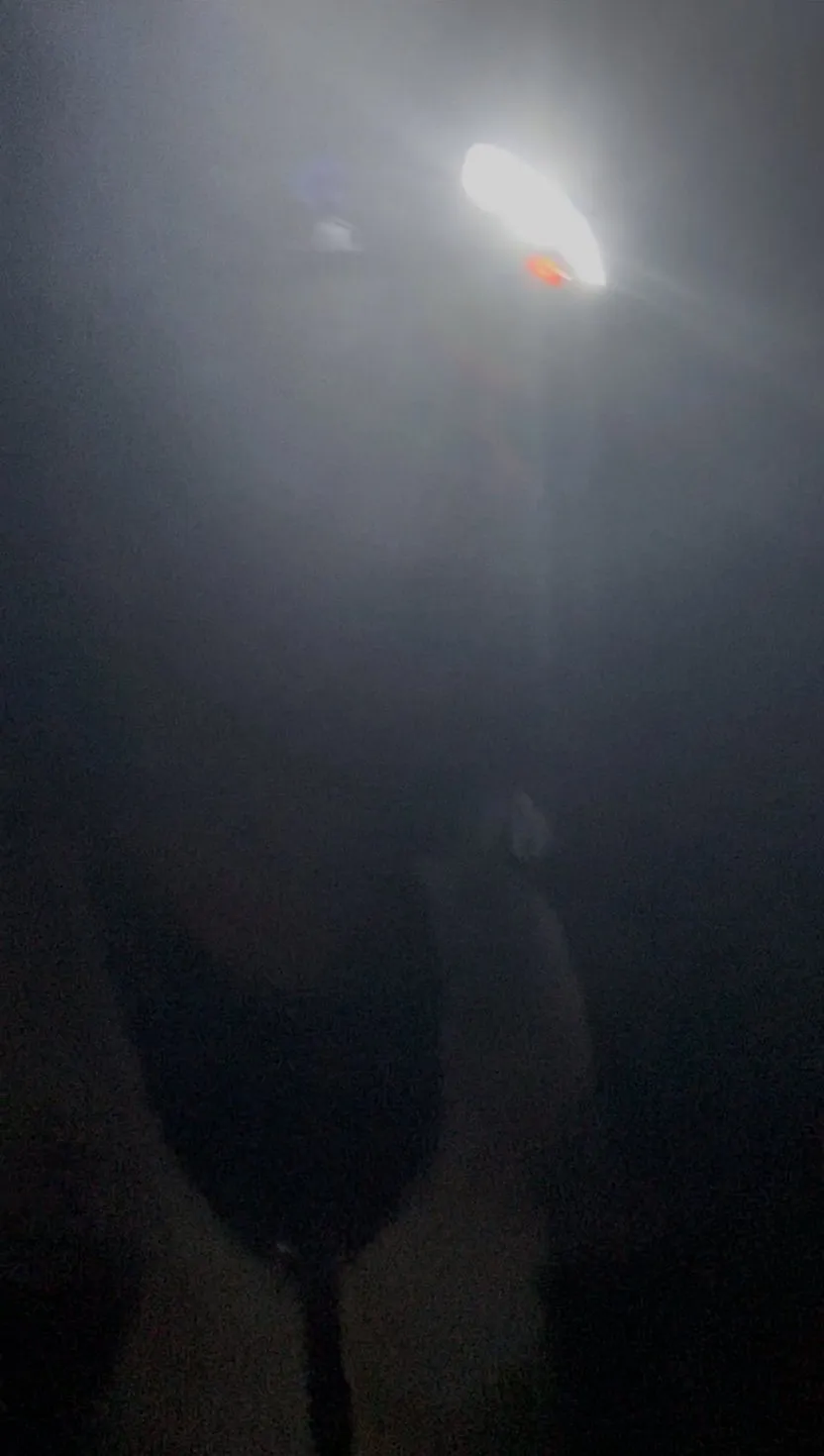 Une frontale allumée dans un brouillard épais, de nuit, pendant l’UTMB Nice