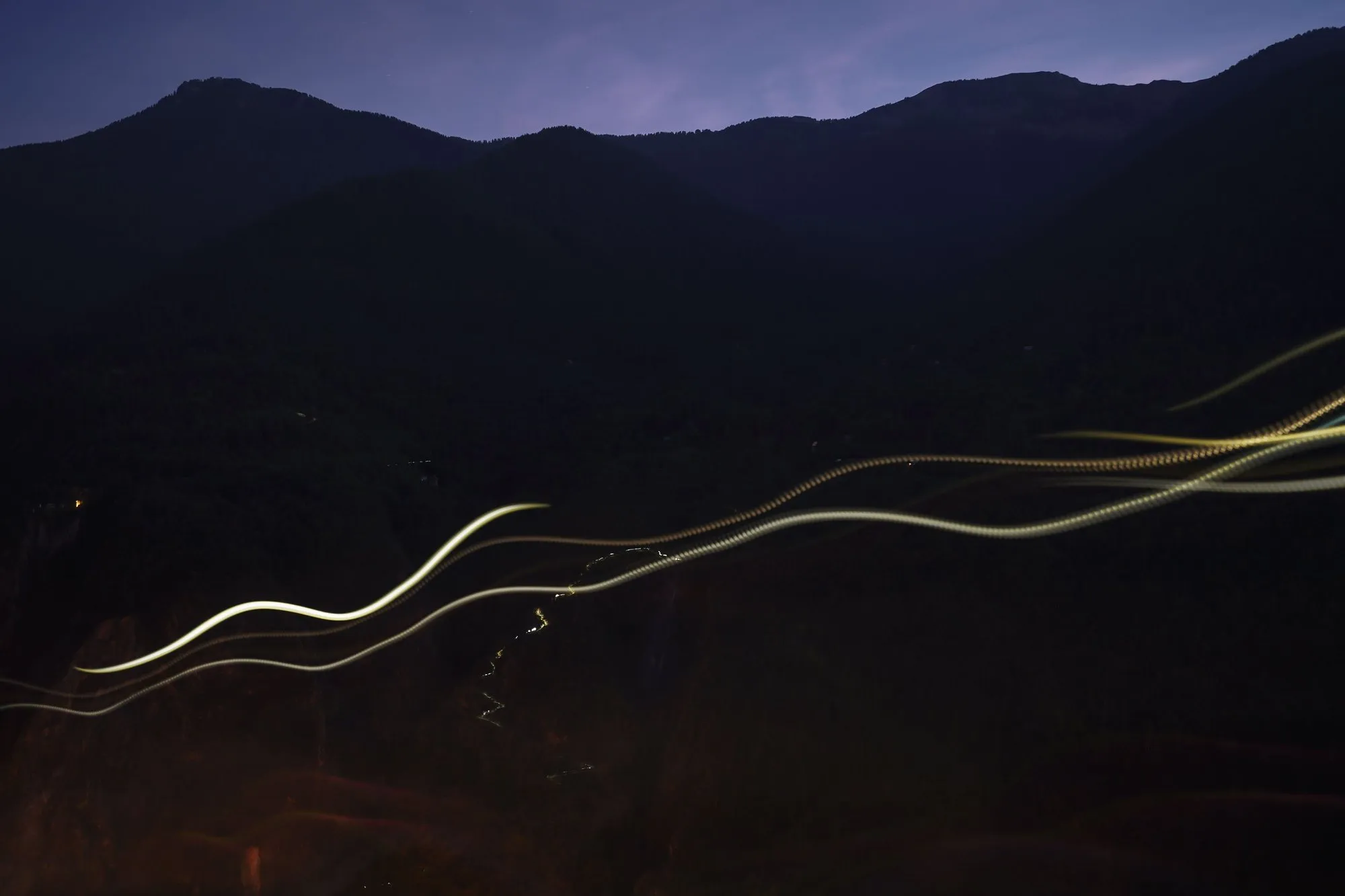 Traînées lumineuses des lampes frontales des coureurs dans la montagne, de nuit, pendant l’UTMB Nice